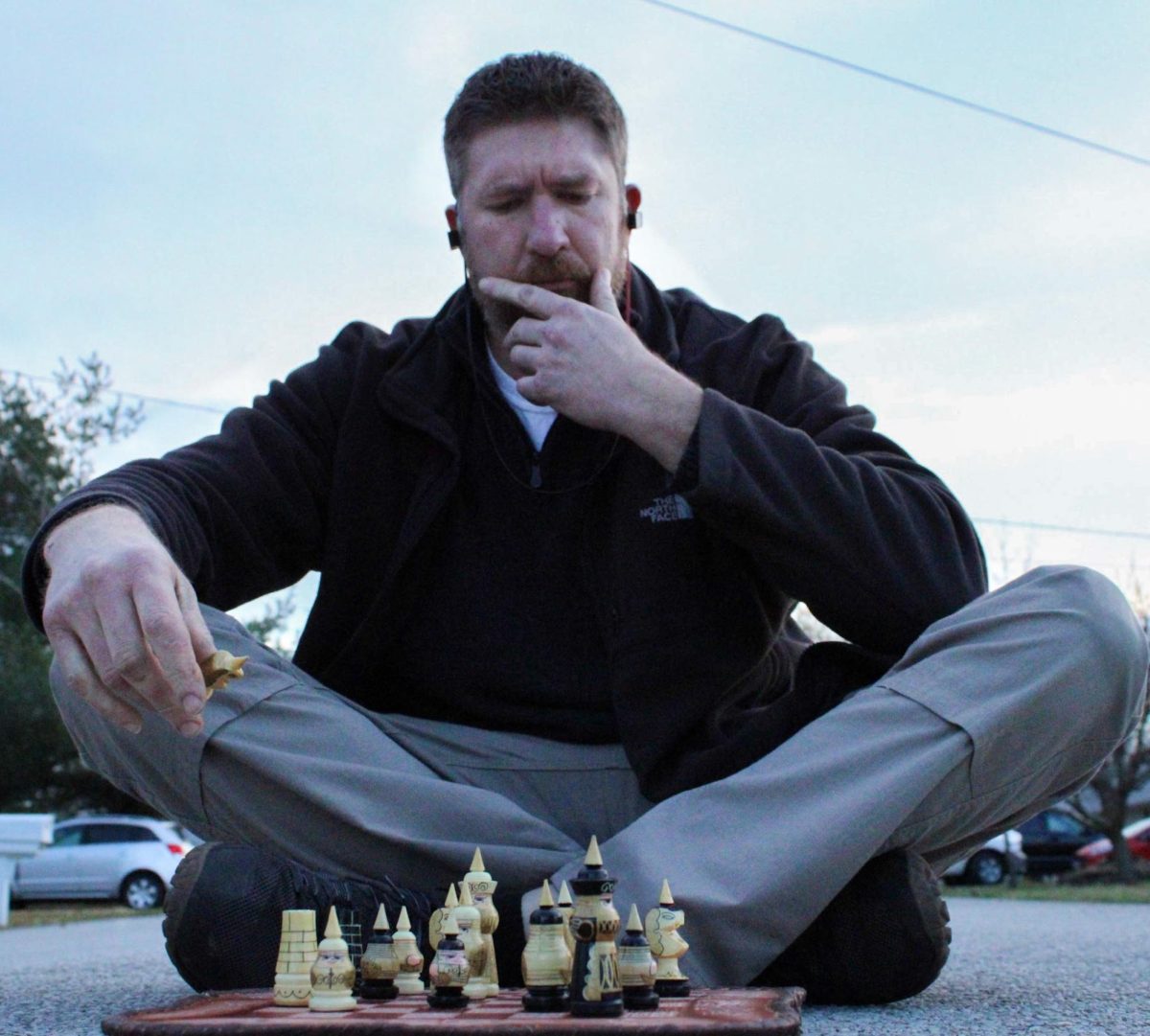Parent Aaron Bearup thinks about what his next move is gonna be in a game of Chess, while playing in the middle of the road.