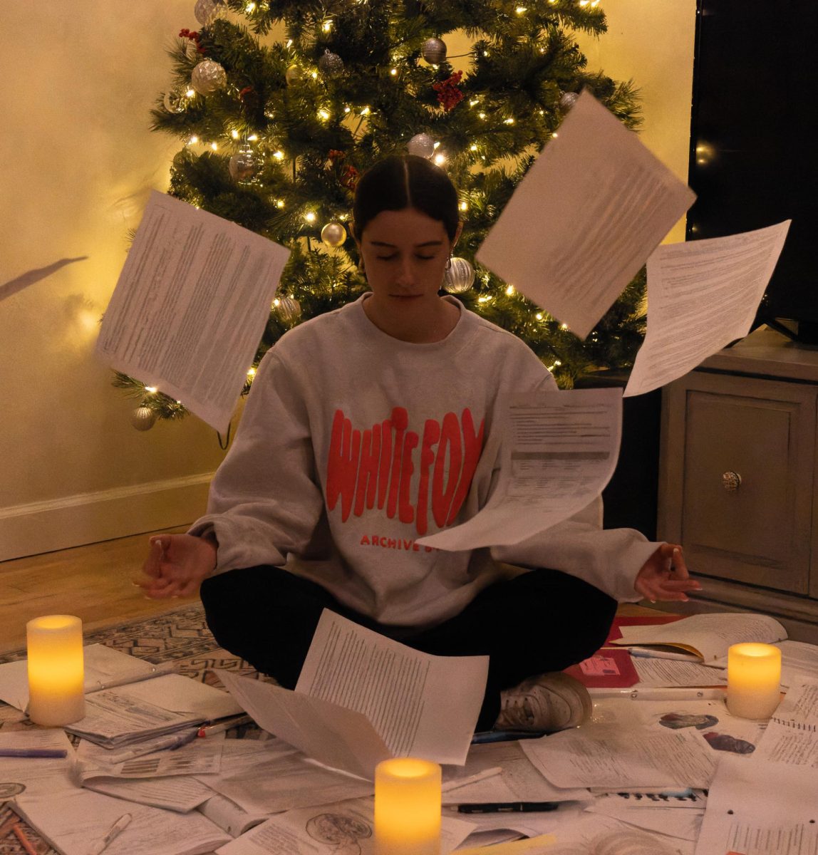 Junior Madison Scott sits in front of the Christmas tree meditating as she is surrounded by her schoolwork. We wanted to create a scene that shows someone being calm in a very stressful environment. 