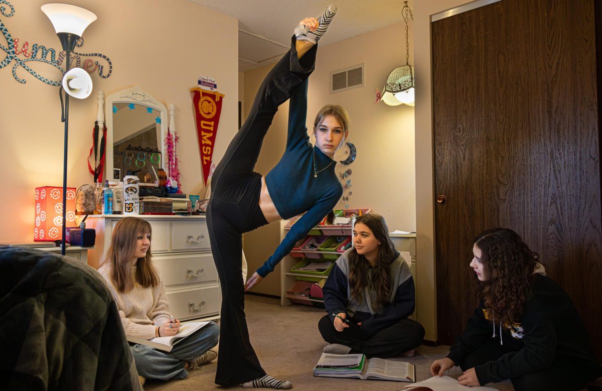 Junior Sophia Allen tries to distract a study group with her dance moves. She struck a pose by holding her leg high while standing in the middle of the group. 