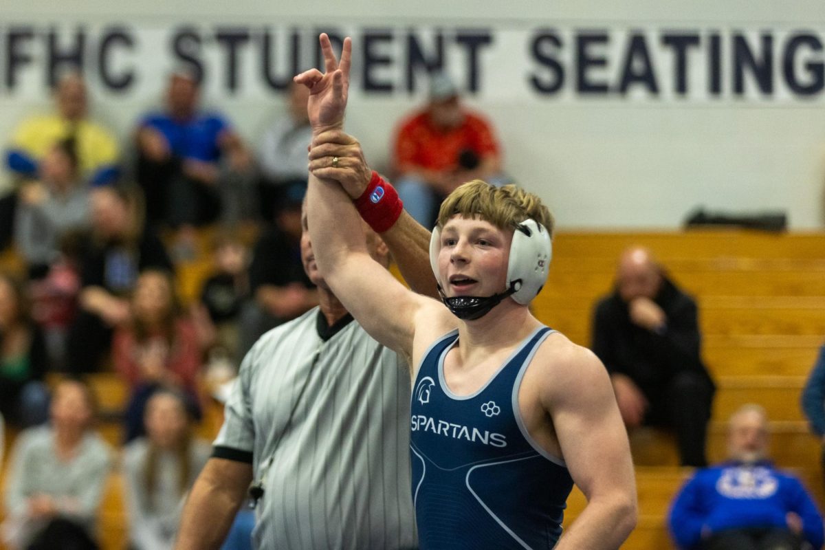 The referee holds senior wrestler Noah Keens arm up in victory following his win. 