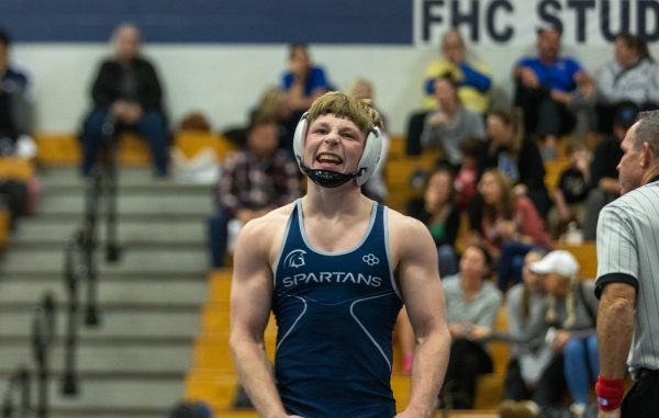 After winning his match, senior Noah Keen flexes in excitement as the crowd cheers him on. 