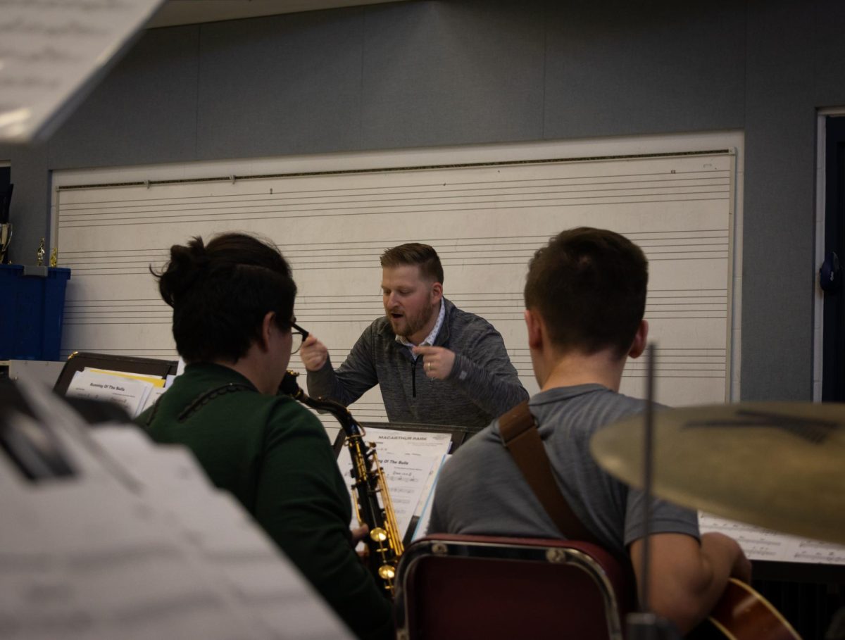 Mr. Steck leans over his stand, conducting the band. He studies the score, making note of any improvements that can be made. 
