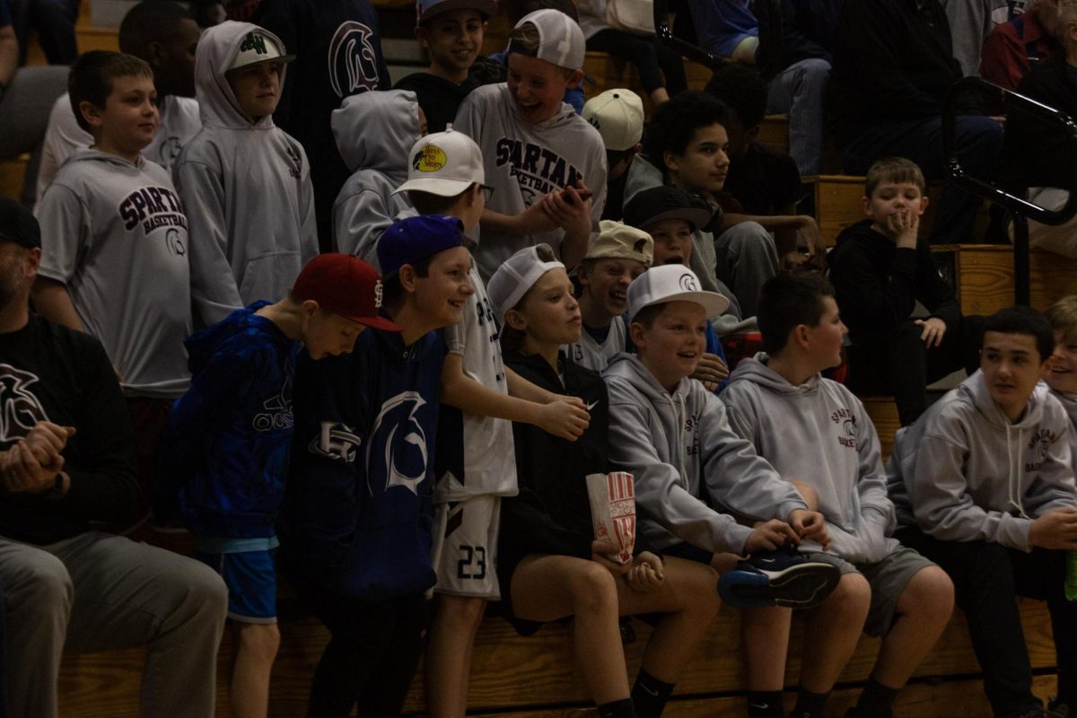 A group of young Spartans fans sit together and celebrate when the team shoots and scores two points. There were many young fans who showed up to support Francis Howell Central at the game against Troy. 