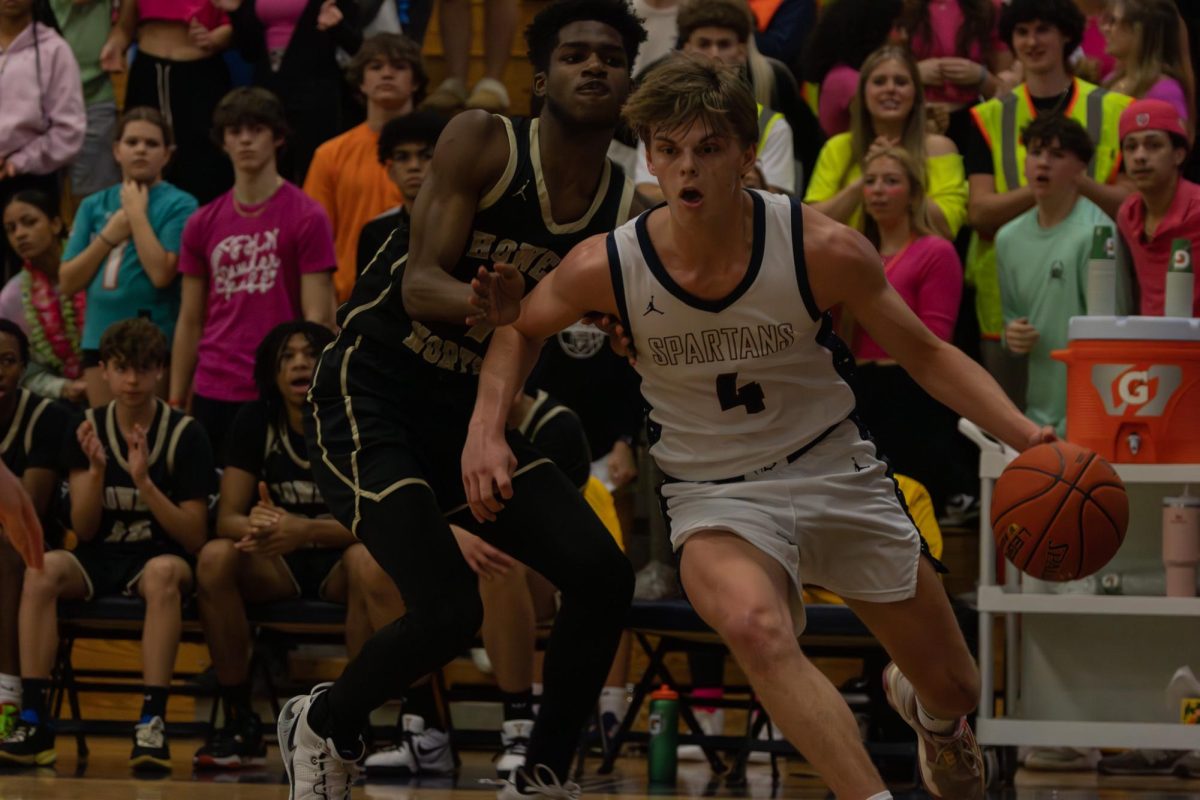 Senior Nate Rush dribbles the ball past a FHN defender in order to make his way to the basket for a shot on March 13 during the senior night game. 