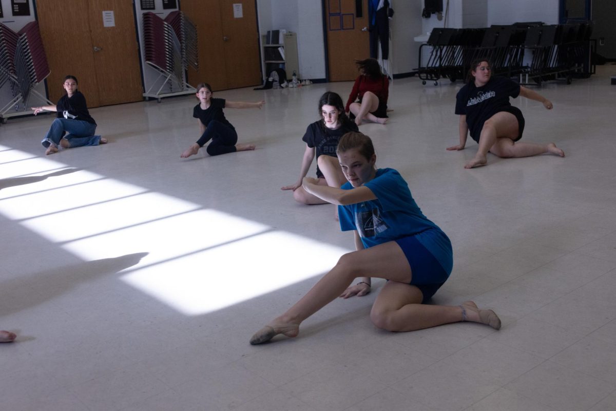 On+April+11+at+the+new+marcher+camp+for+color+guard+members%2C+junior+Katelyn+Kohler+swipes+her+foot+across+the+floor+as+she+teaches+her+group+how+to+do+her+dance+choreography.+The+group+of+new+middle+schoolers+who+are+interested+in+color+guard+copy+her+movements+before+they+perform.