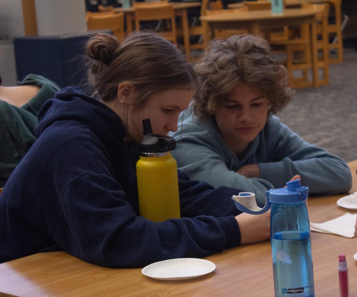 At+the+Gateway+Voters+celebration%2C+freshmen+Amelia+Heidt+and+Ryan+Latta+eat+their+donuts+together.+They+decide+which+book+to+vote+for+while+they+hangout+in+the+library+on+April+10.