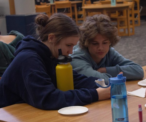 At the Gateway Voters celebration, freshmen Amelia Heidt and Ryan Latta eat their donuts together. They decide which book to vote for while they hangout in the library on April 10.