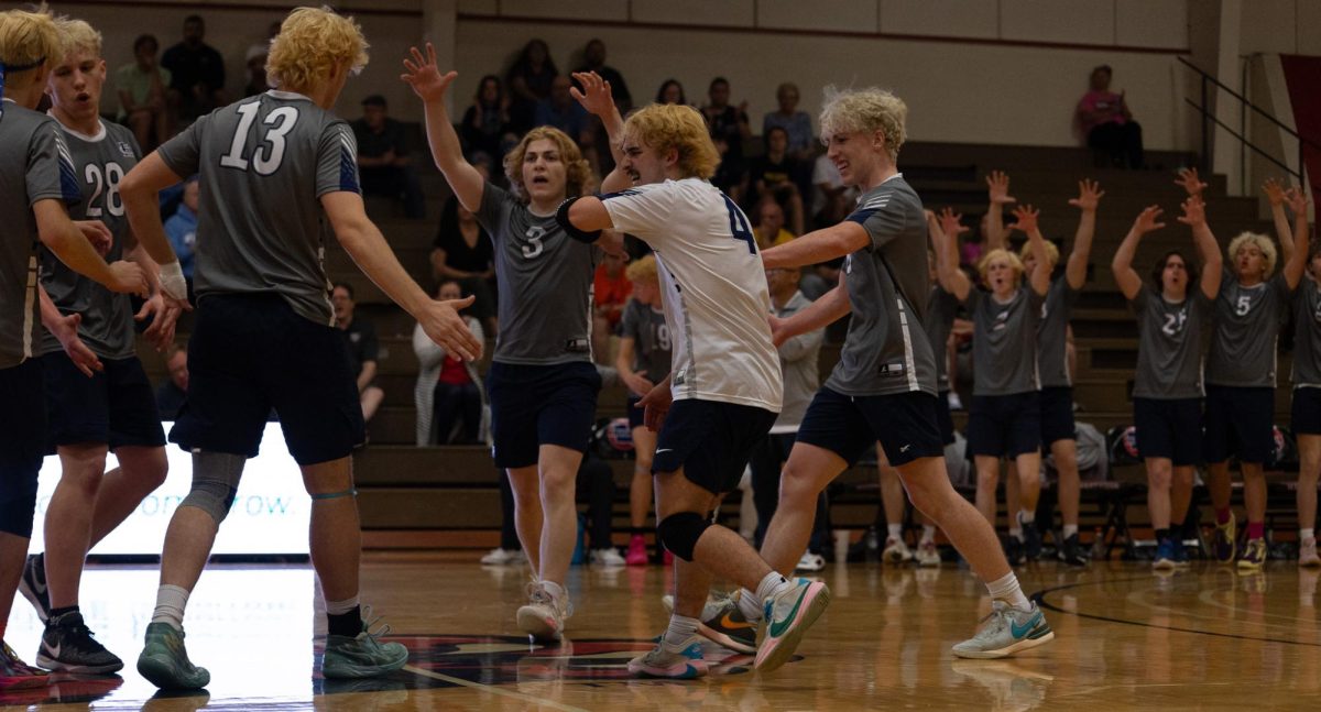 The varsity boys volleyball team comes together on the court to celebrate after a successful block in the finals match. Lafayette had many players over six feet so blocking was difficult.
