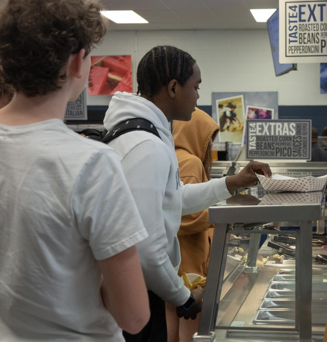 A student customizes his lunch with the available options in the cafeteria.