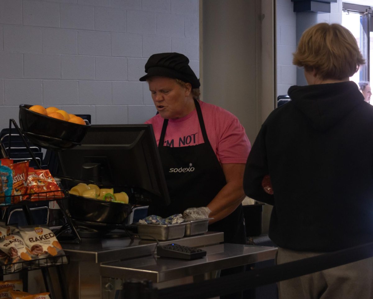 A lunch lady works through the line of students waiting to check out.
