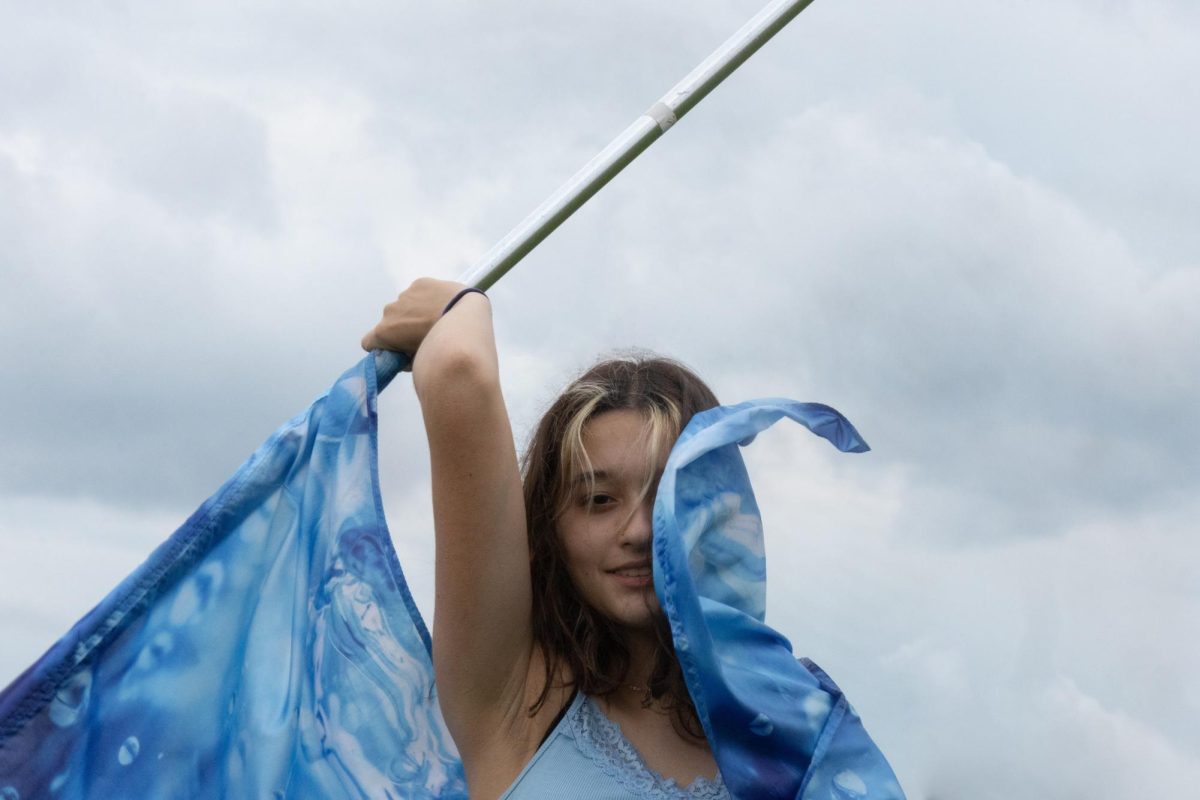 On a cloudy day in spring, junior Macy Sand spins her flag behind her head. The light blue silk swipes across her face as she cracks a small smile. The blue that surrounds her represents her flooding passion that she pours into color guard. As the blue fills her world, all she can see is her flag.