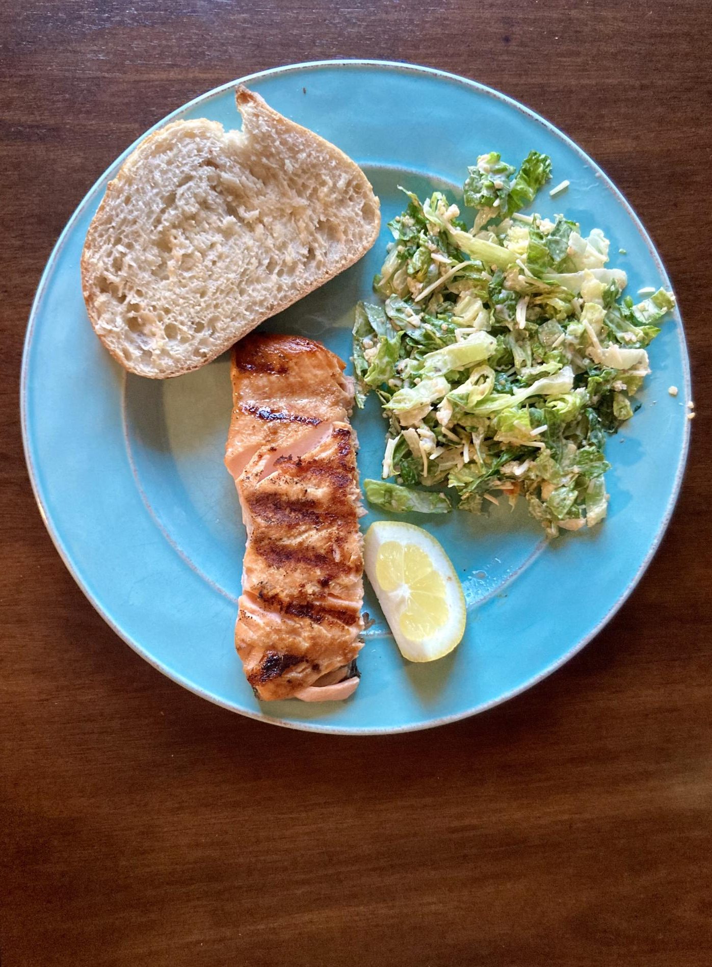 Grilled salmon with Caesar salad and bread.