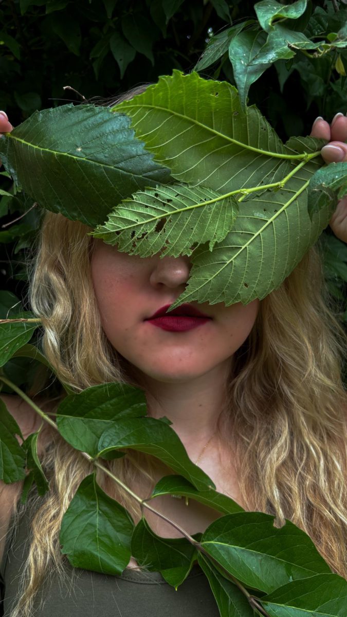Junior, Lydia Nelson’s eyes are covered by leaves, as she is swarmed by nature the dark red lip stands out. The dark red represents passion and intensity which describes Nelson perfectly. 