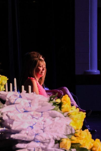 Teresa Odle, the guest speaker at the NHS induction ceremony and English teacher at FHC looks out at the current speaker giving a speech. With induction flowers in sight, the focus is centered on the people on stage.