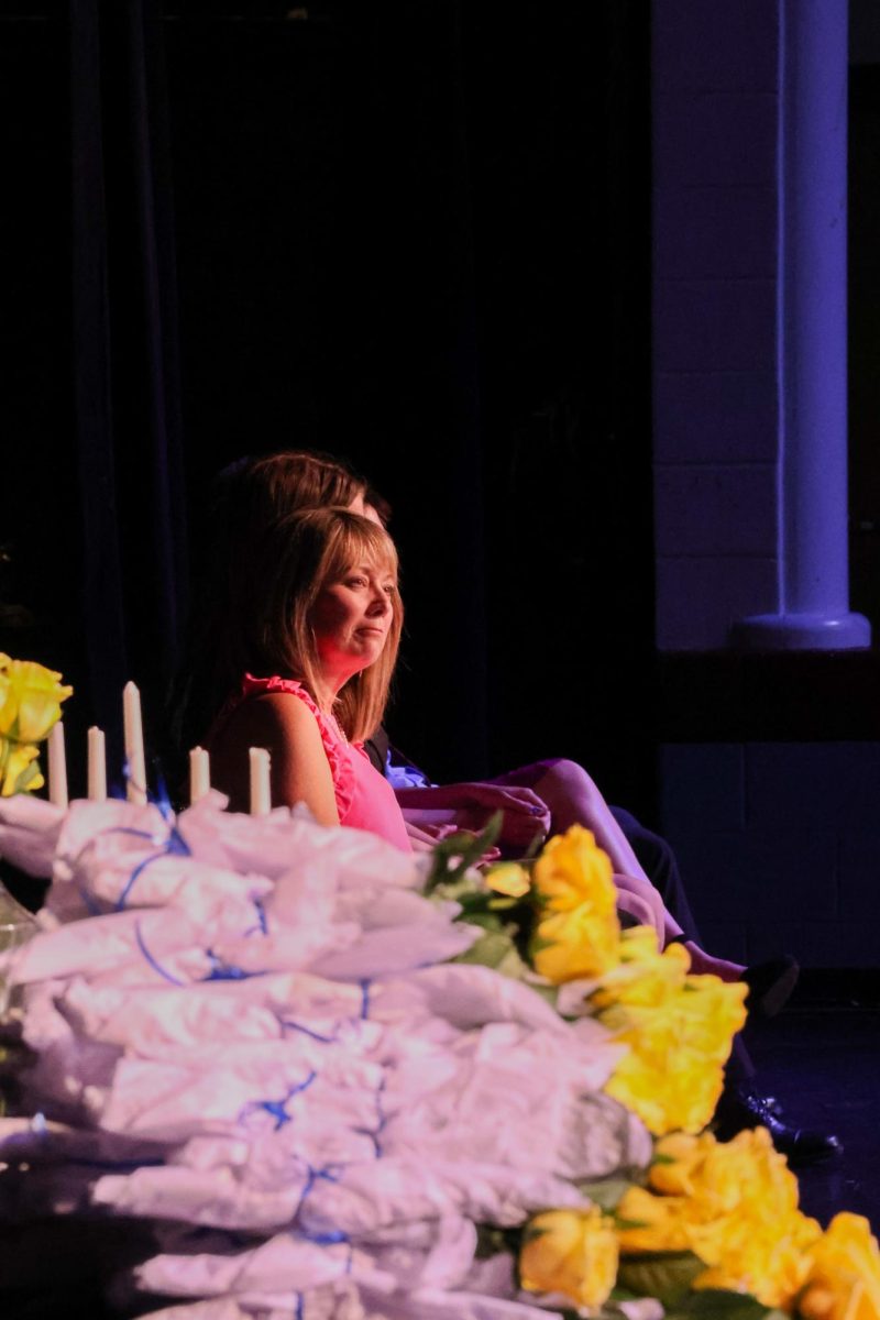 Teresa Odle, the guest speaker at the NHS induction ceremony on May 1 and English teacher at FHC looks out at the current speaker giving a speech. With induction flowers in sight, the focus is centered on the people on stage.