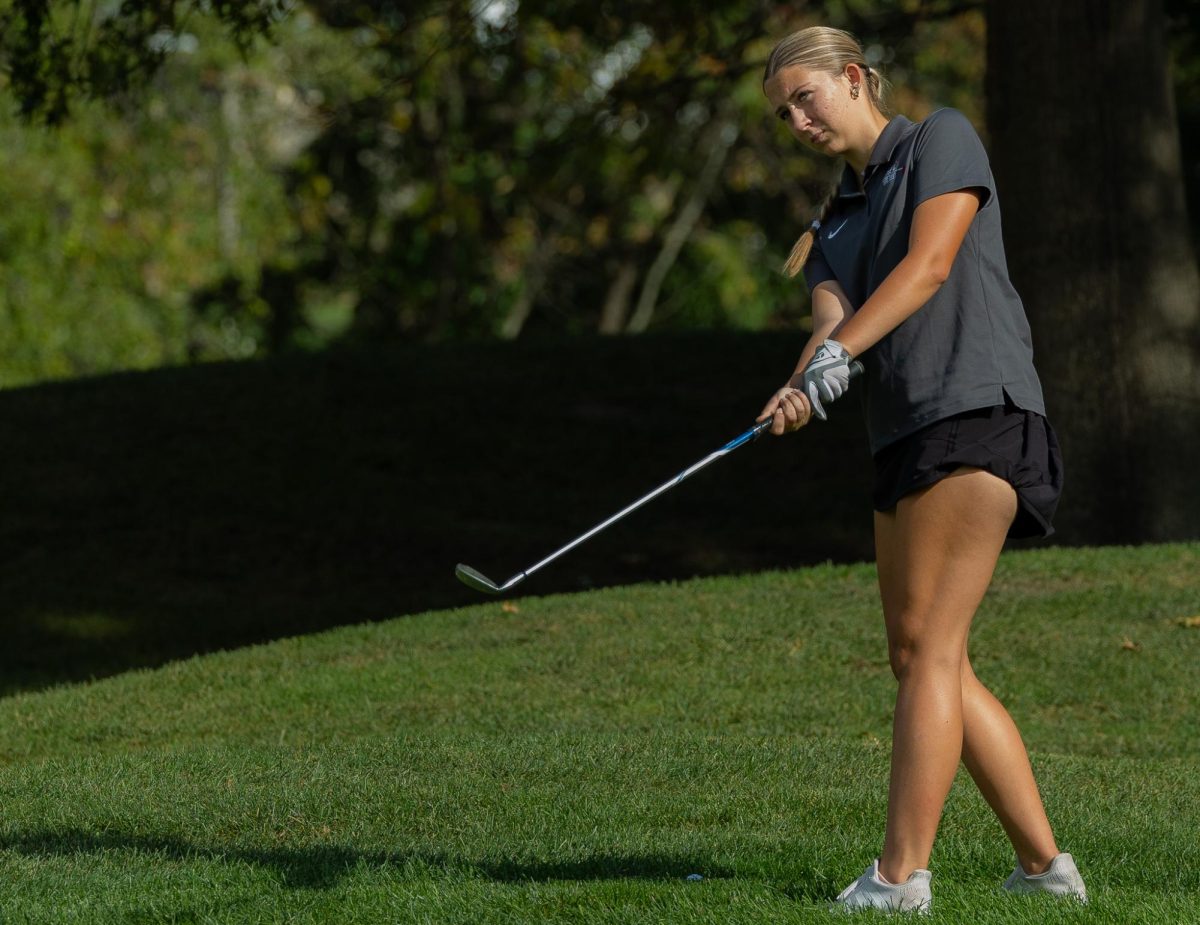 Junior Emma Lange raises her golf club to visualize the path of her golf ball. By doing this Lange planned out her strategy to hit her ball to make it reach the pin of the first hole during the match against Francis Howell North on Sept. 19. 