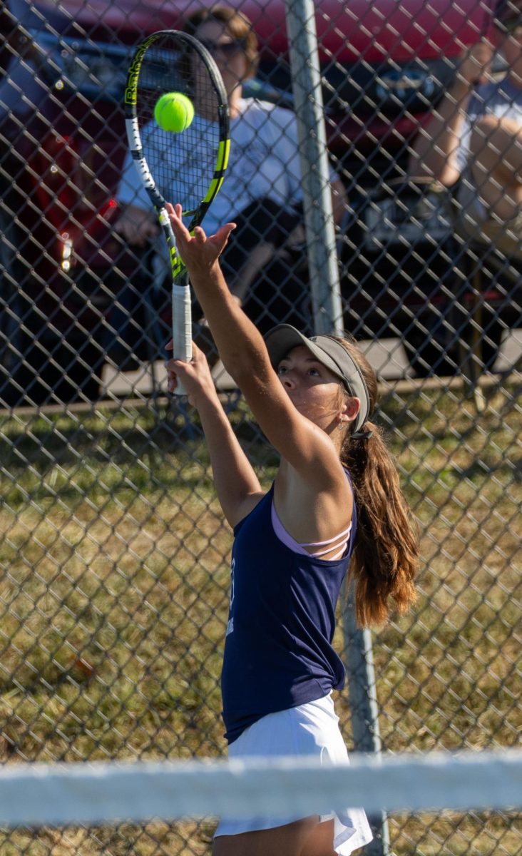 Ashley Hayes tosses the ball high in the air, preparing to serve. Hayes served an ace, meaning the ball landed in the court before Helias could get to it. 