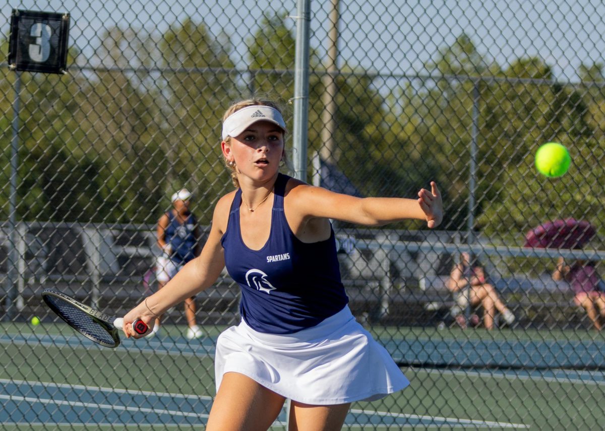 Anticipating the hit, Isabel Black swings her racquet backwards and steps to the ball. Black hit the ball and lobbed it to the opposite side of the court. 