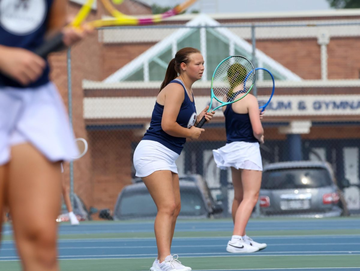 In position, captain senior Kaitlyn Morgan waits for her partner to serve the ball. She keeps her guard up in preparation for the other side to return the serve back.