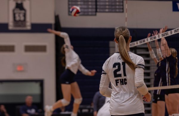 Senior Logan Rubel watches in anticipation as her teammate spikes the ball over the net. The opposing players jumped in the air to attempt to block the ball. 