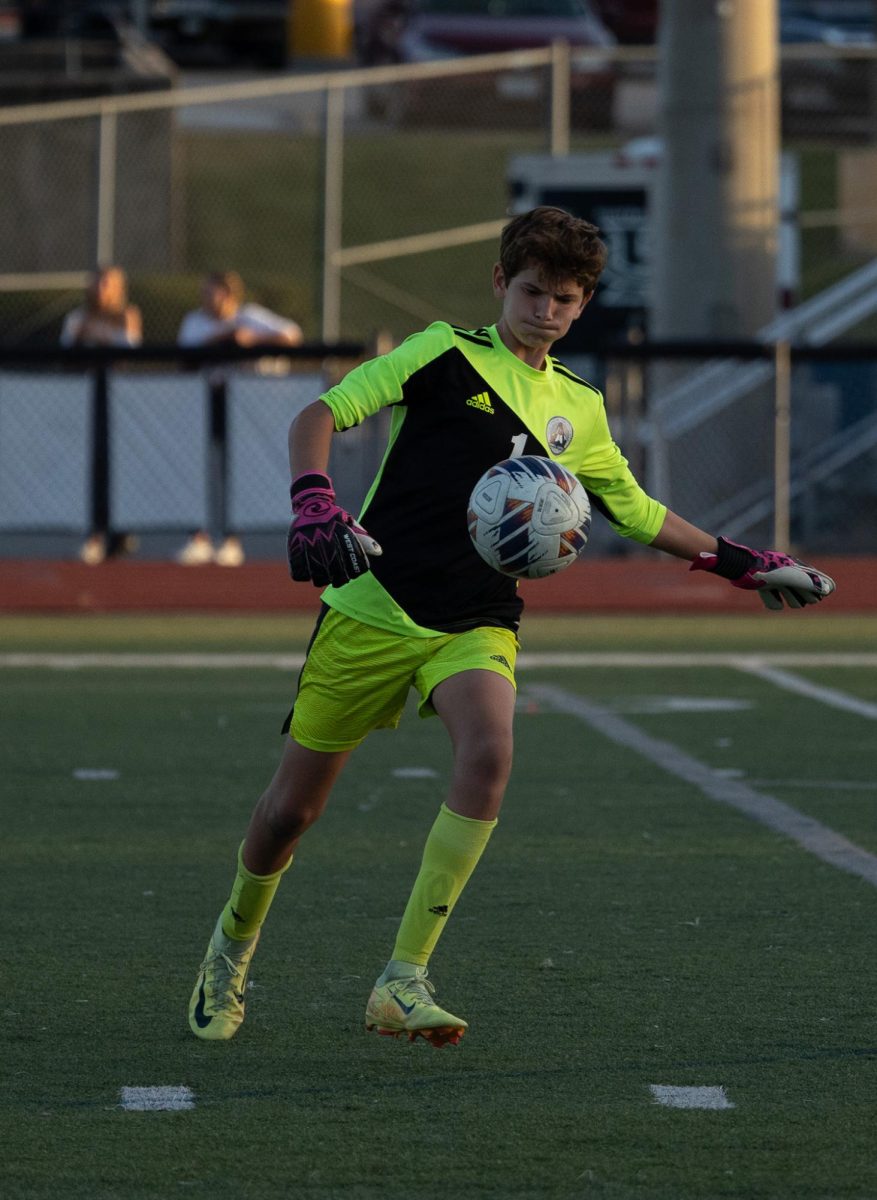 Freshman Jack Morris dropkicks the ball away from their goal, punting it to one of his teammates. The goalkeeper struck the ball up the field, giving his teammates an advantage.