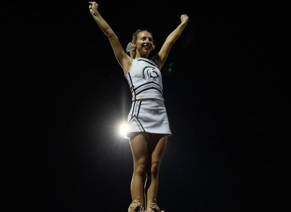 Junior Reagan Wania holds her arms up and smiles brightly at the crowd. This was during the cheerleader’s halftime performance.