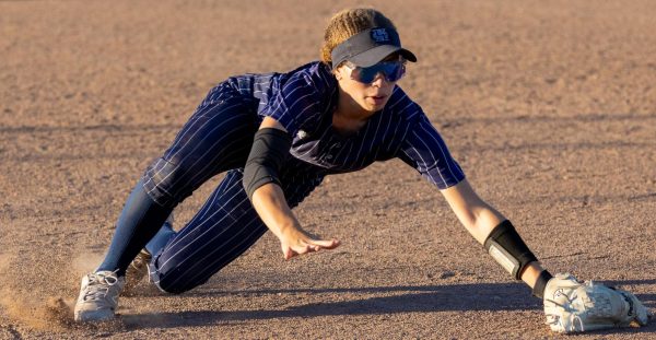 Freshman Nola Patterson drifts into the dirt and propels her arms out to intercept the ball. Patterson sent the ball flying to first base, hoping to tag the runner out.