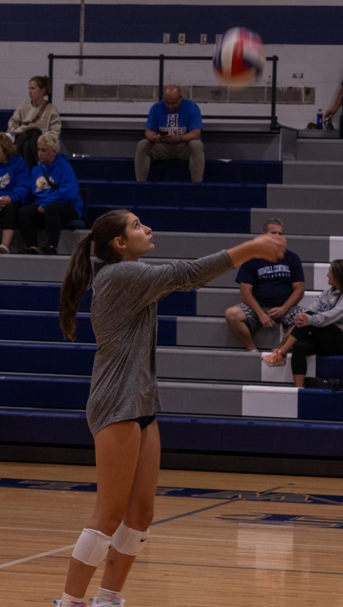 Dressed in her warm up uniform, junior Mae McAdow works on receiving the ball after hard serves or hits. During warmups the girls went back and forth between bumping, setting and spiking the ball.