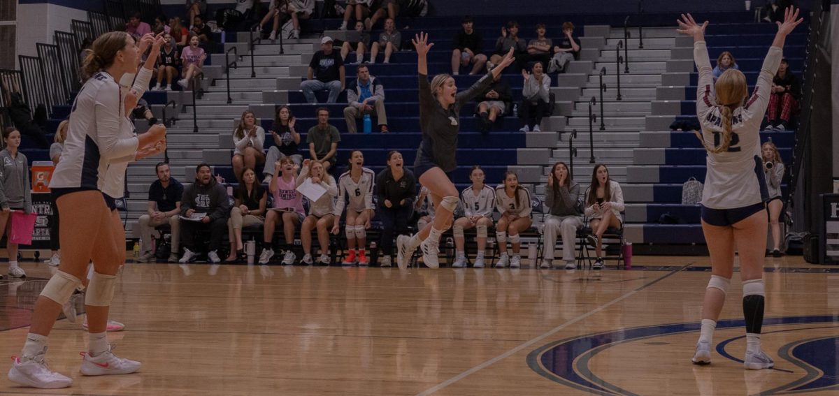 Following a drawn-out point, senior Addie Henderson and her team jump and cheer in excitement. On Sept. 24, the girls volleyball team faced Howell in a close back and forth battle, eventually losing the set 3-2.