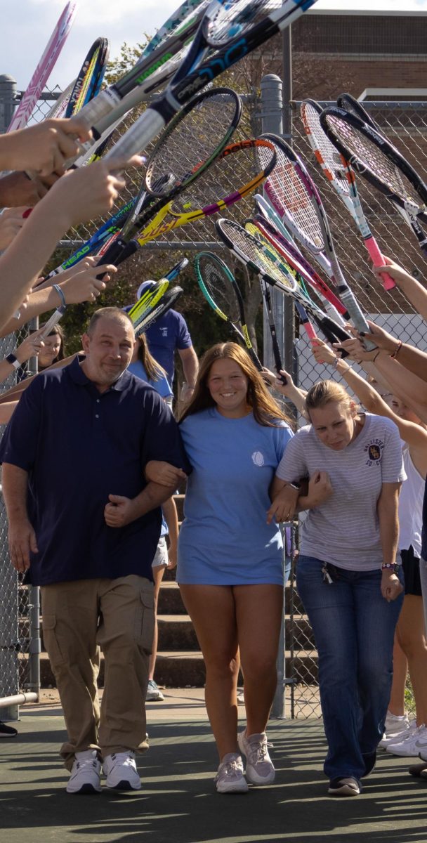 Kaitlyn Morgan ducks under the tunnel of racquets, along with her parents. The senior night celebration marked the closing of a hard-fought season.
