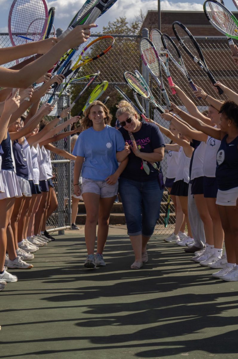 Senior Sophie Rosser smiles with her mom as they walk towards the coaches to receive her medal. The underclassmen on the team created a tunnel with their racquets for the seniors to walk under. 