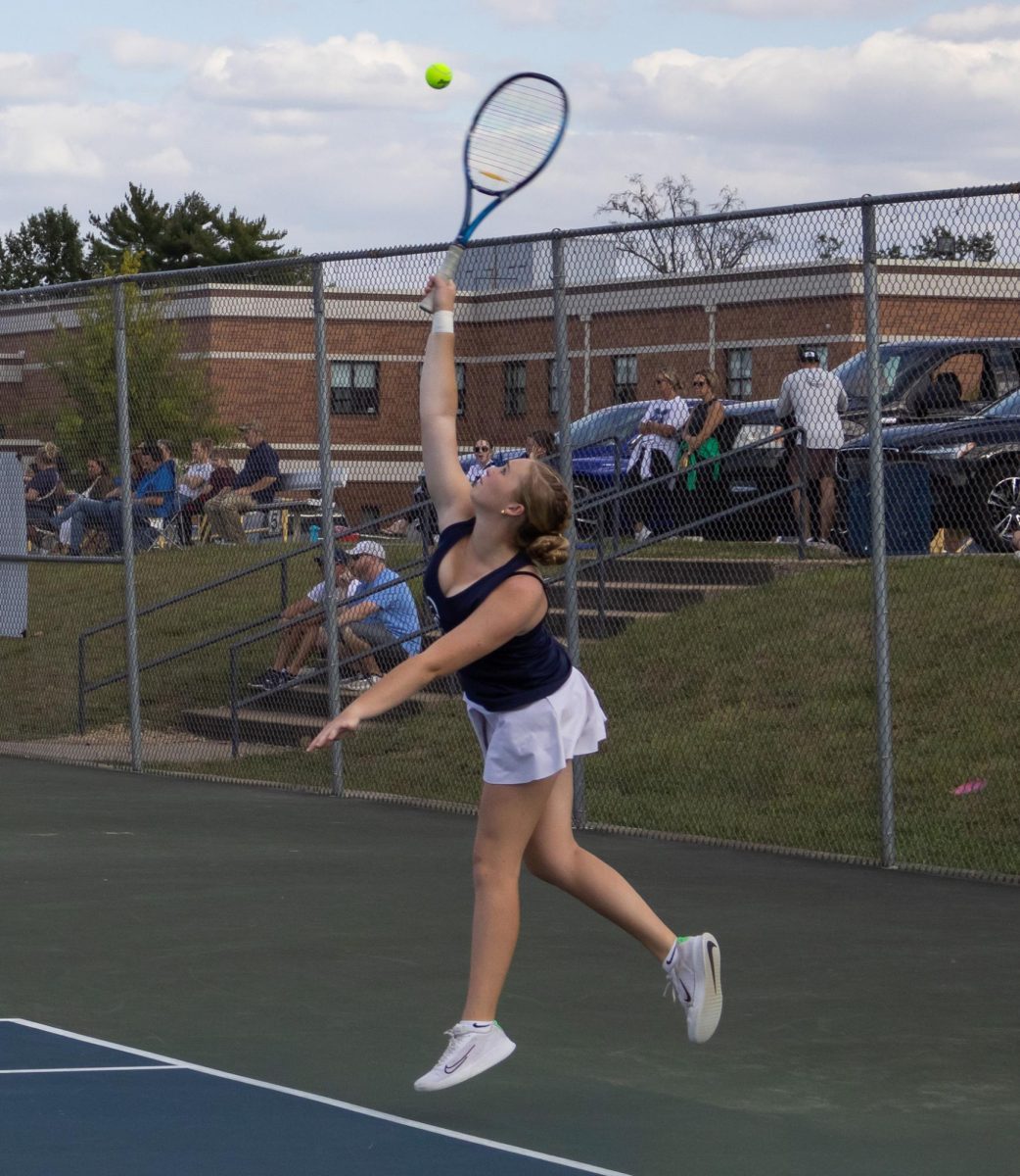 Sophomore Chloe Horton jumps to reach the ball for her serve. Though the night celebrated the seniors, underclassmen still competed in matches.