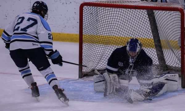 Junior Tyler VonFeldt gets sprayed with ice by an opposing player who was stopping very fast in front of him, pushing the net. VonFeldt cupped the puck in his glove, ensuring the other team didn't score. 