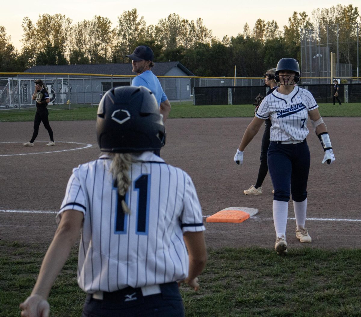 Sophomore Izzy Dunlap walks off the field towards pinch runner senior Holly Crass. Dunlap had just hit a single and then had to go change into her catchers gear.