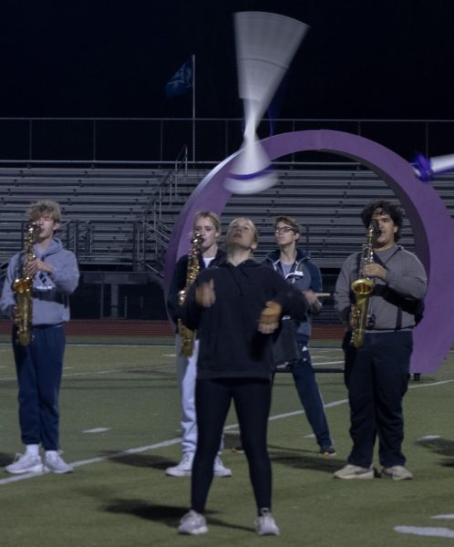 As she stands in front of the saxophone section, sophomore Amelia Heidt throws her rifle into the air. The colorguard often stands in between the percussionists and the rest of the band during their performances.