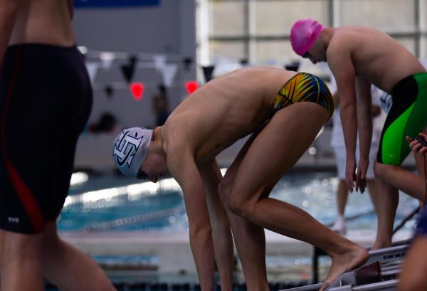 Preparing to dive into the pool, freshman Dryden Finley gets into the diving position. He swam the butterfly following his entrance into the pool.