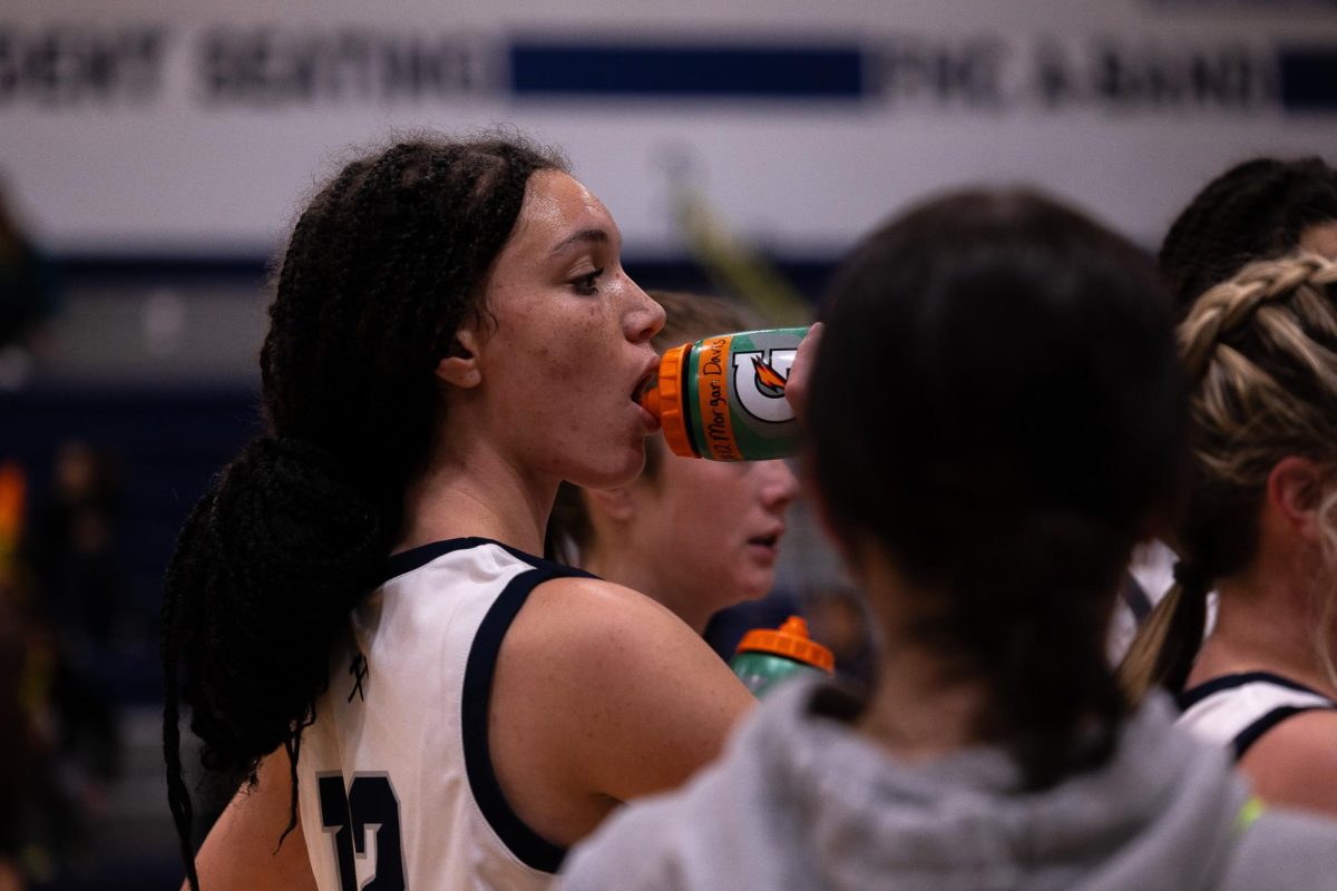 Senior Morgan Davis sips from her water bottle and concentrates on Coach Hayley Leake’s pep talk during a time-out. The team played aggressively, taking a victory of 63-20.