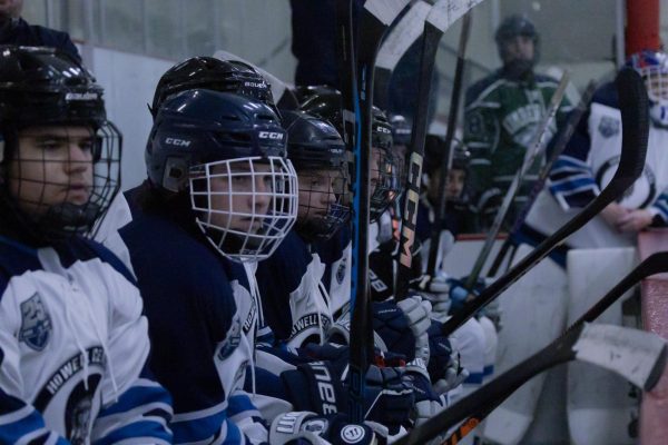 As the game kicks off, the boys on the bench watch their line out on the ice. Making sure to hit the boards with their sticks when a celebration or a “good job” is needed.