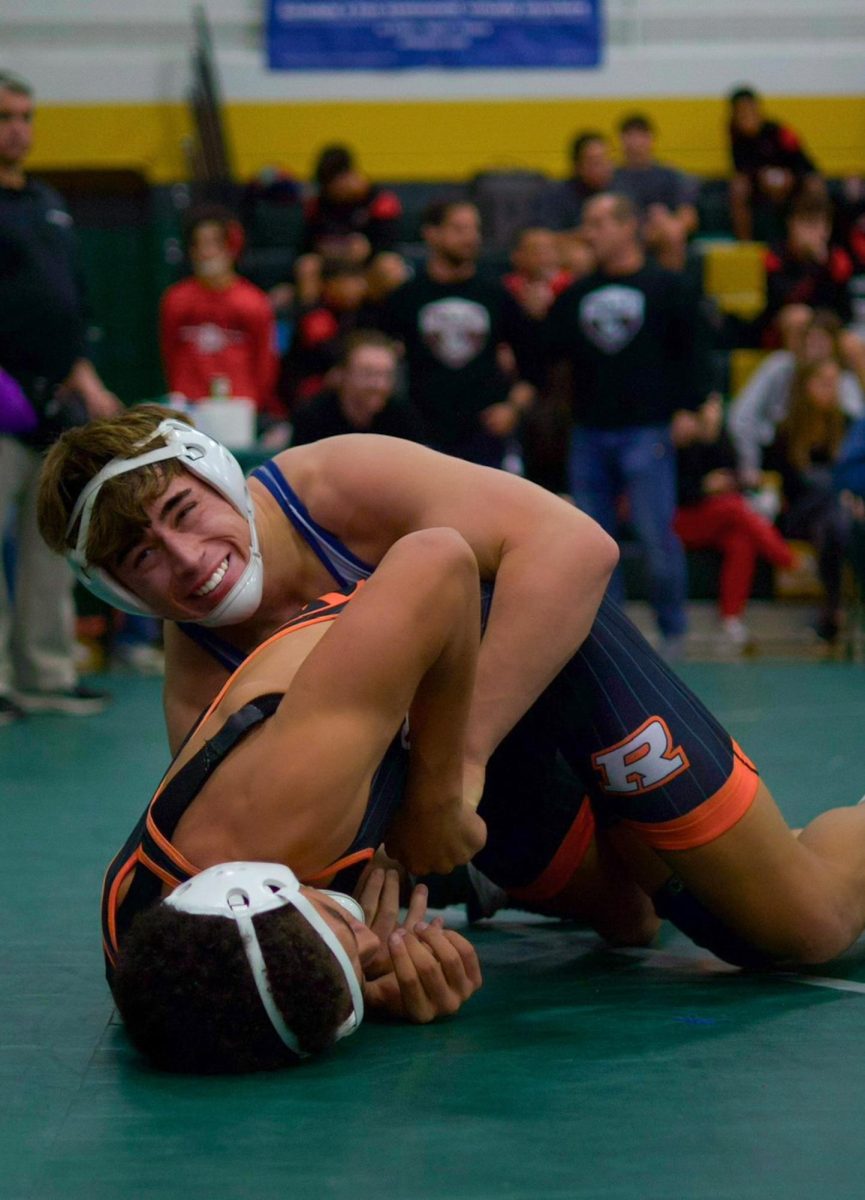 During his first match of the day, senior Owen McCracken winces in pain as his opponent lays on his leg. McCracken was able to flip his opponent on his back, freeing his leg and pinning his opponent down.
