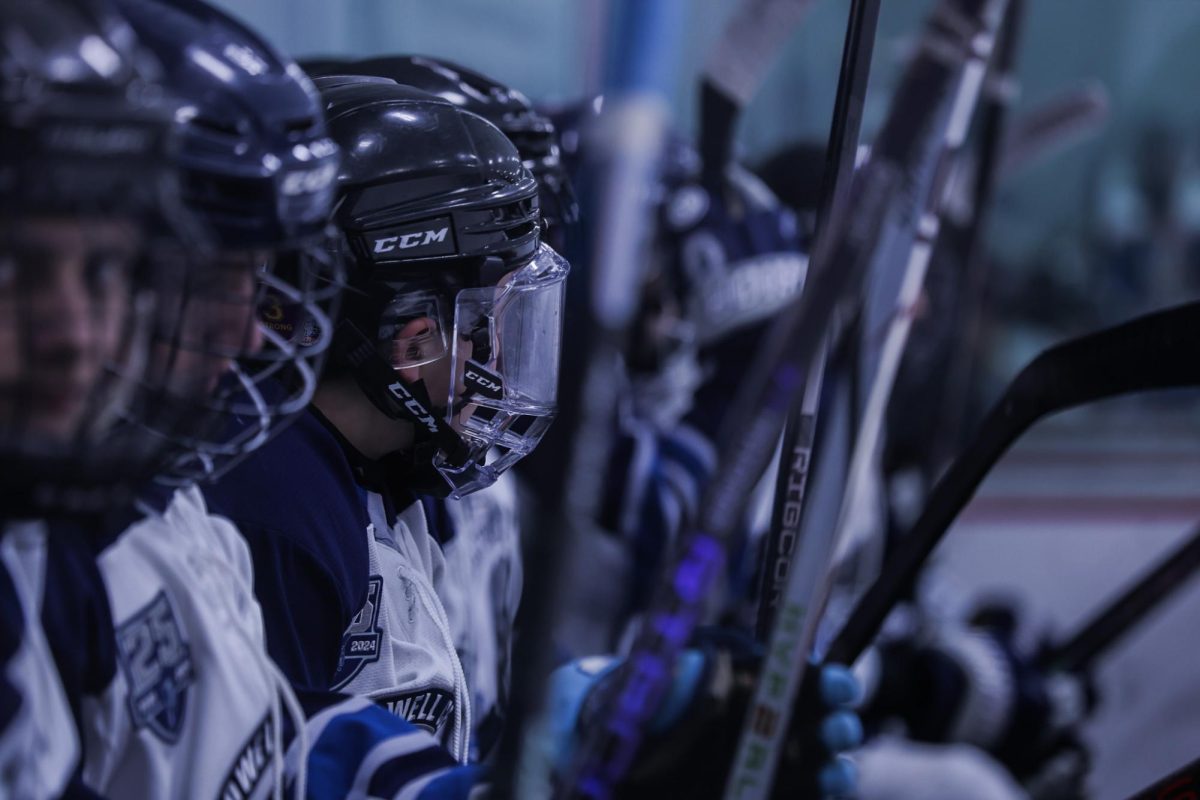 The team sits on the bench during a break between shifts, exhausted from the game. Sophomore Matthew Grishman turned his head to the side, as he watched the game progress. 