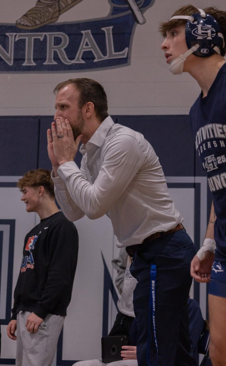 Boys assistant Coach Brian Bitney yells at one of his wrestlers. Bitney then turns and talks to junior Chase Gray about the match.