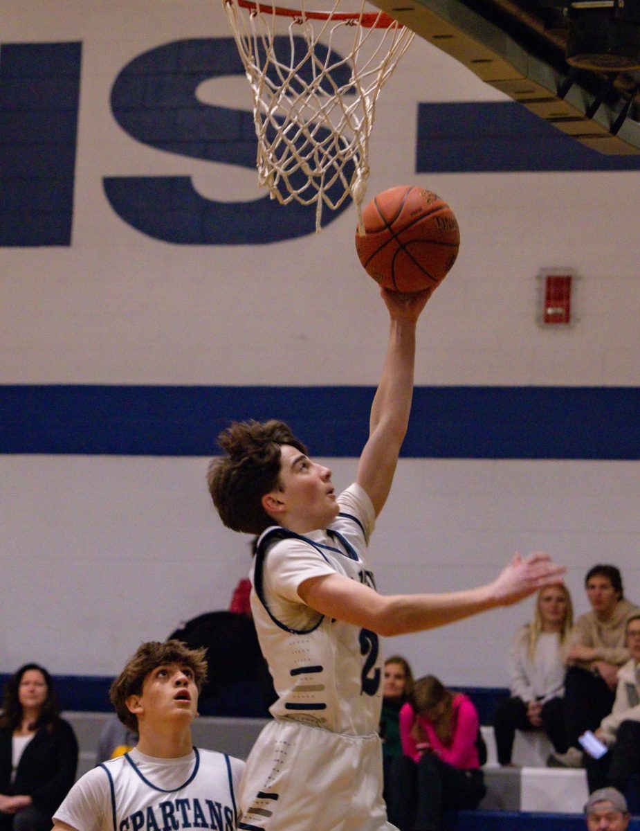 Reaching for the rim, freshman Lucas Miller looks to score for the Spartans. After a quick step around his defender, Miller was left with a clean look under the basket. 