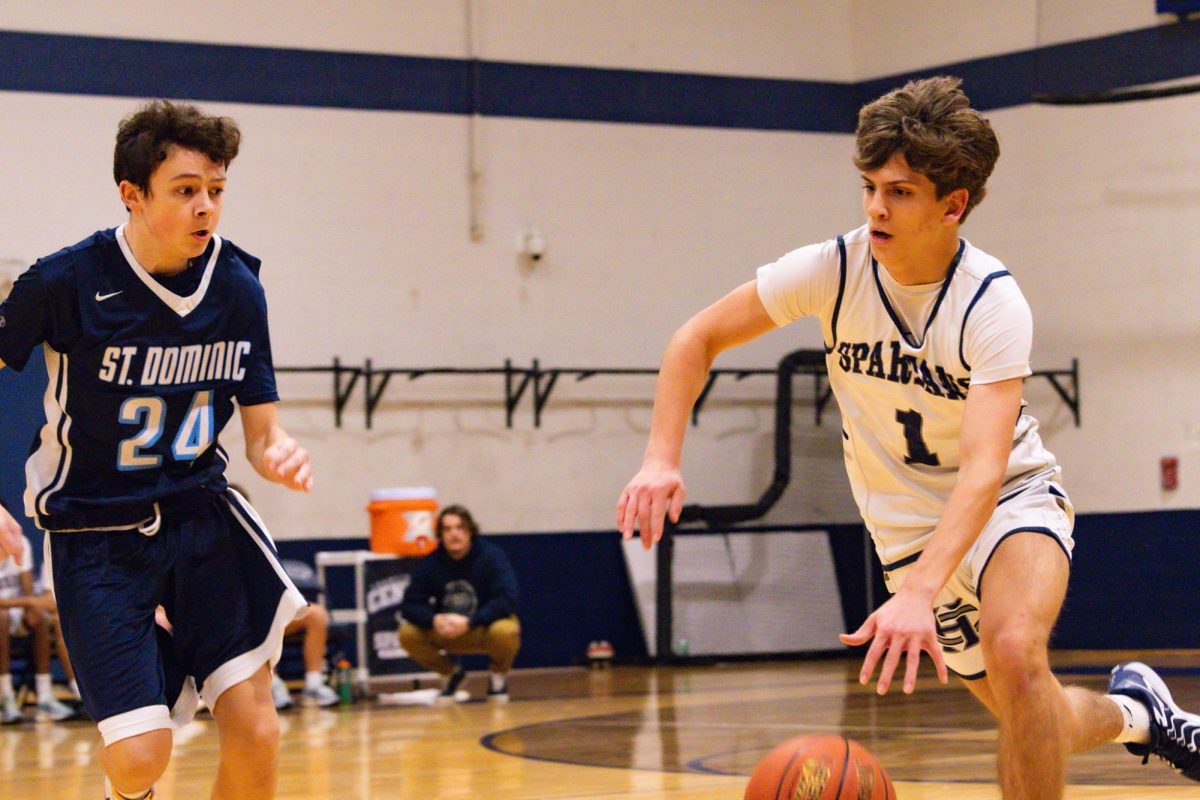 Freshman Will Schuster dribbles past a defender to break the St. Dominic press. Pushing the ball up the sideline, Schuster looked to advance it to an open teammate.