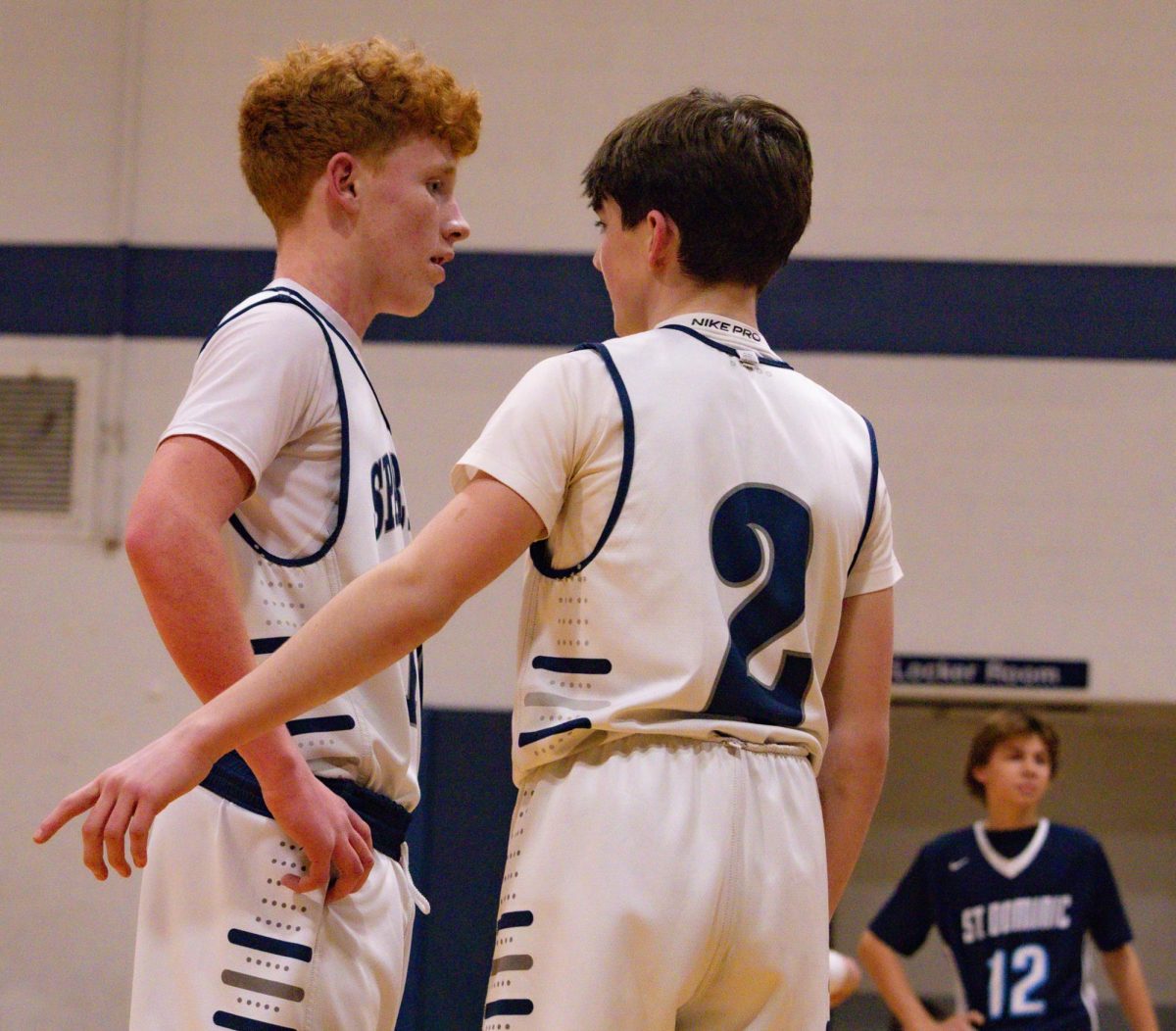 While a teammate prepares to shoot free throws, freshman Lucas Miller speaks with his teammate, freshman Owen Rothermich. Miller pointed to the sideline as the two discussed an adjustment. 