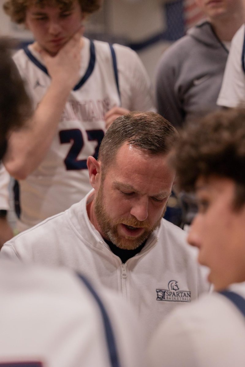 Head Coach John Varner looks down at his notebook before telling his team what play he wants them to run. Varner then broke the huddle and sent his team out back on the court. 
