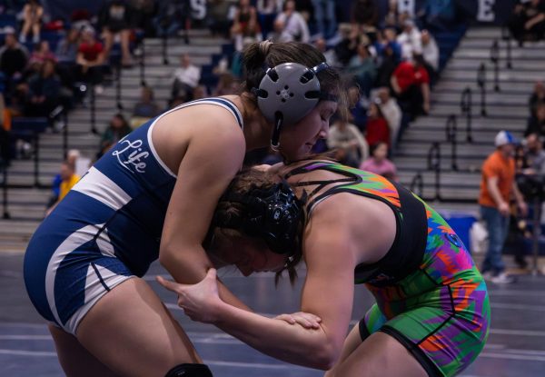 Senior Olivia Tran strains to hand fight her opponent and ultimately get her in a position that makes it to where Tran can take a shot. To take a shot means to get your opponent on the mat and prevent them from getting back up in the hopes to win by pinning them down.