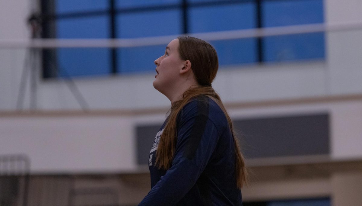 Senior Kat Mann stares up at the net and watches as the net swishes during warmups. Mann practiced her shot before getting off the court to practice defense against her teammates.