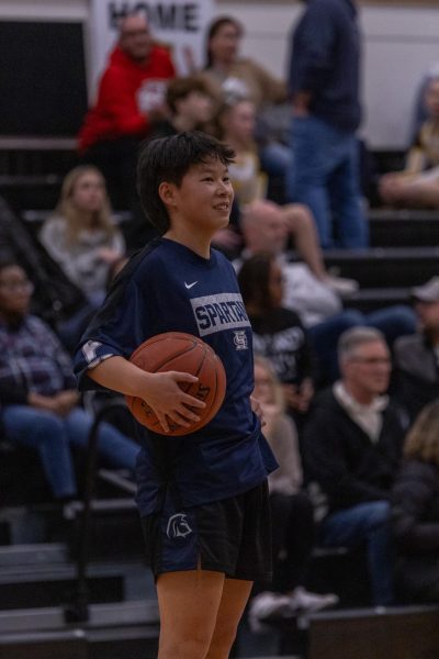 Smiling at her teammates, sophomore Izzy Brewer holds the ball on her hip. Brewer laughed with her teammates and got most of her reps within the corner of the court.