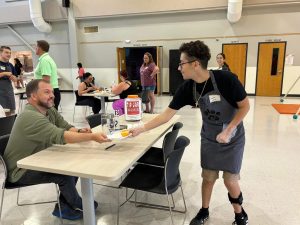 Andrew Lopez hands out an order to a customer during one of the Black Cat Coffee Cafe's pop-up events. The Cafe gives its special needs employees many opportunities to practice their skills in a real-life setting during events like these.
Photo courtesy of the Black Cat Coffee Cafe.