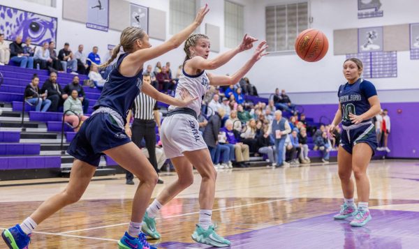 Avoiding her defender, Riley Henderson passes the ball to her teammate playing in the center of the court. As the player in center is only allowed to stay in their spot for three seconds, the player shot immediately after receiving the pass from Henderson.